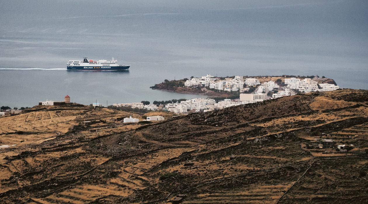 Scenic view of a ferry sailing near a Greek island under blue skies